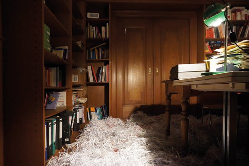 The floor of an office is covered in scraps of paper.