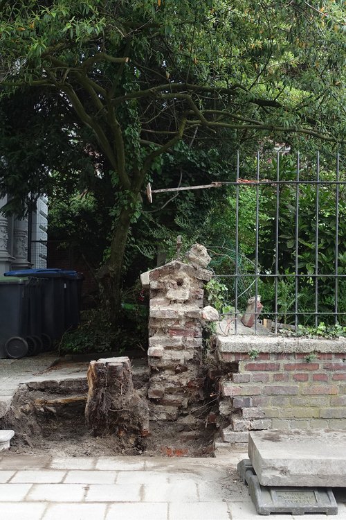 A partially demolished pillar of a garden wall can be seen in the centre of the picture.