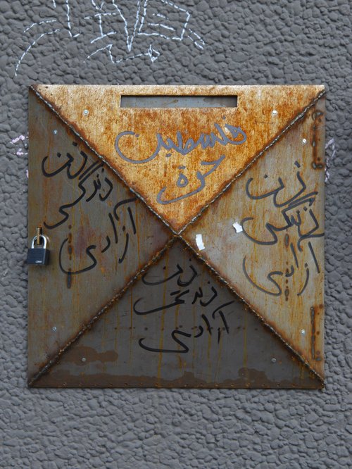 Close-up of the rusted and written-on letterbox.