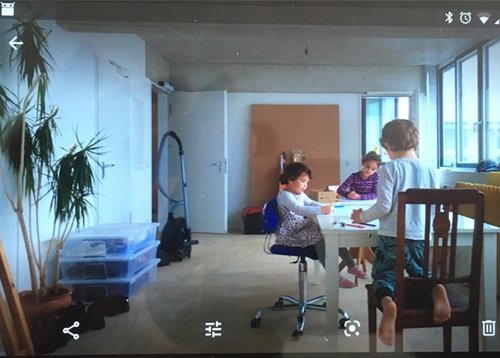 Three children are playing at a table in the centre of a living room.